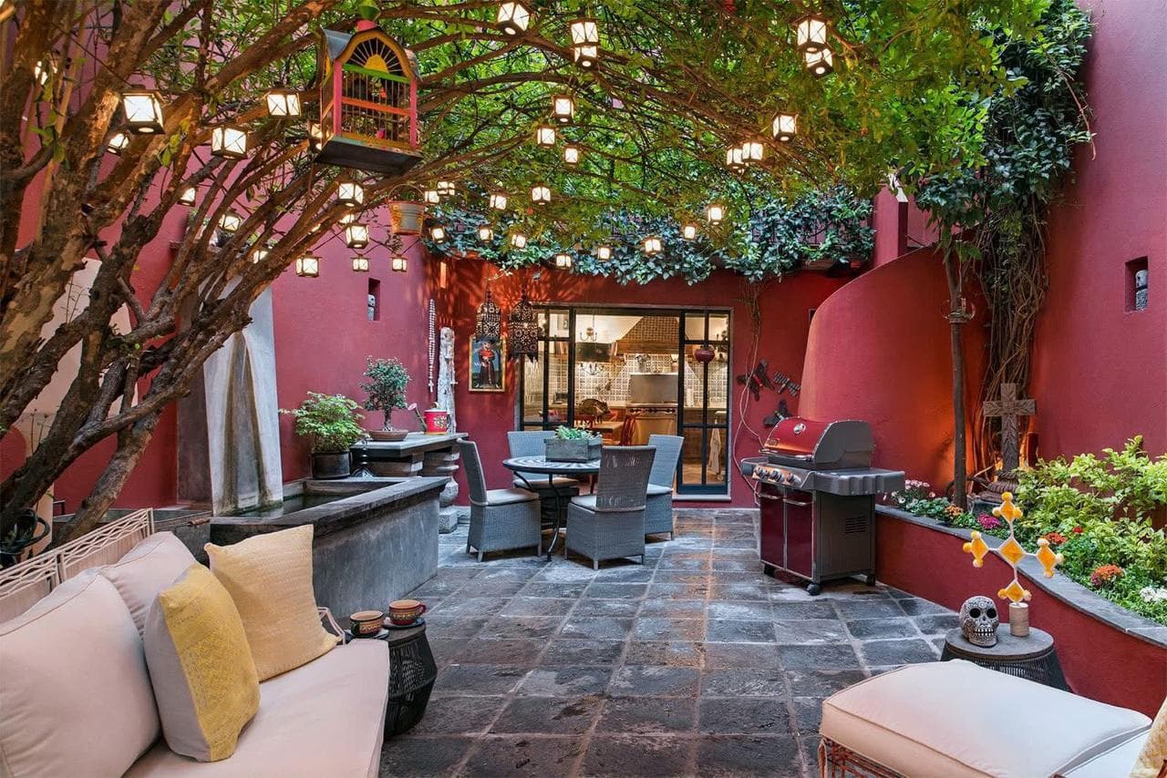 Patio central con muros rojos y bóveda de farolitos colgantes