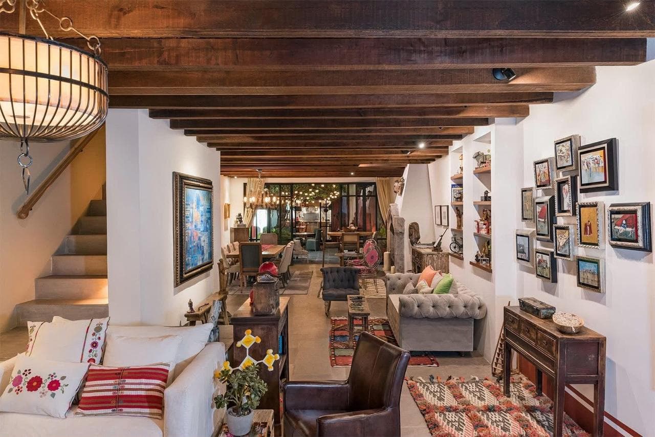 Sala y comedor en planta abierta: vigas, chesterfields y muro-galería de arte